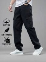 Man standing on a street wearing N Club black baggy cargo jeans with large flap cargo pockets on the thighs and a loose, comfortable fit