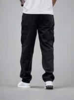 Back view of a man wearing N Club black baggy cargo jeans, showcasing the relaxed fit, back pockets, and panelled knee details