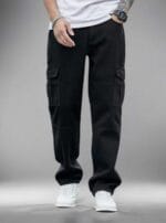 Man standing on a street wearing N Club black baggy cargo jeans with large flap cargo pockets on the thighs and a loose, comfortable fit.